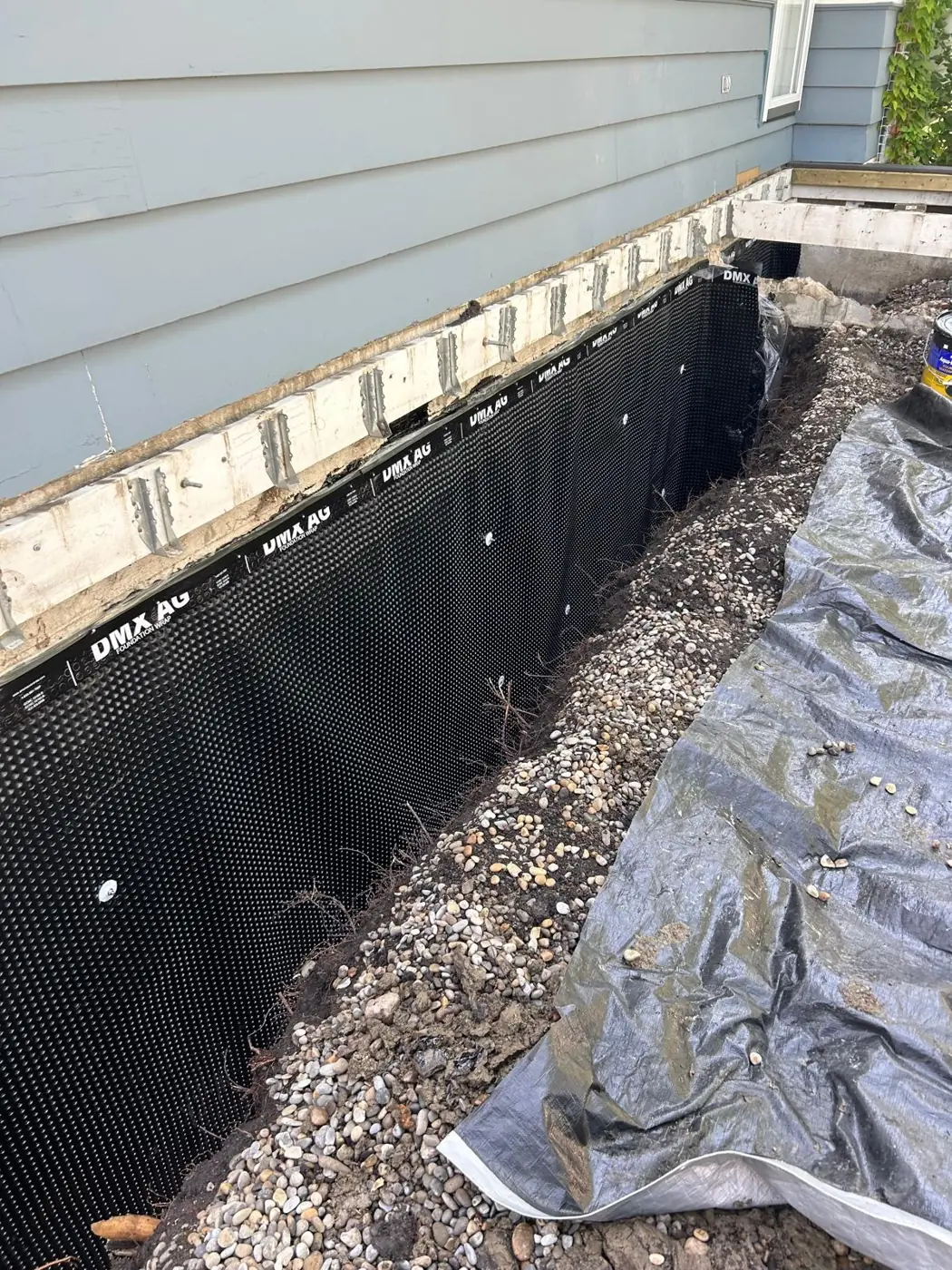 Excavated foundation wall covered in black dimple waterproofing membrane