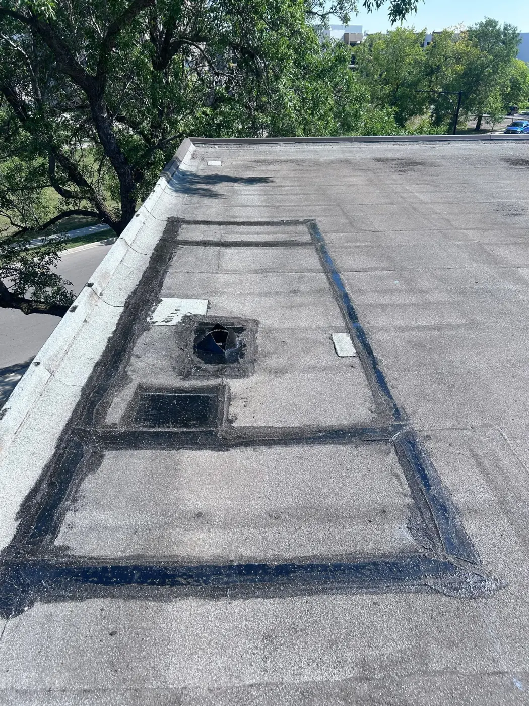 Flat-roof membrane patched around drain & hatches