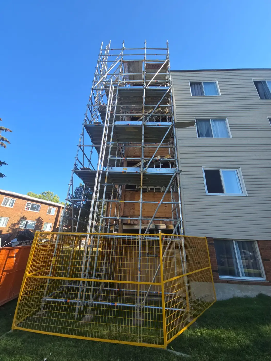 Scaffolding tower against a three-storey apartment building with the balcony stack opened up